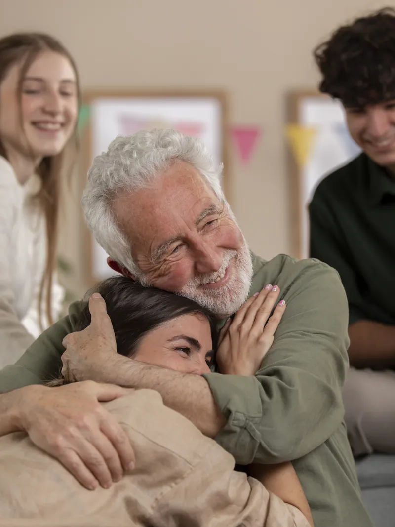 Una familia abraza a su abuelo en casa